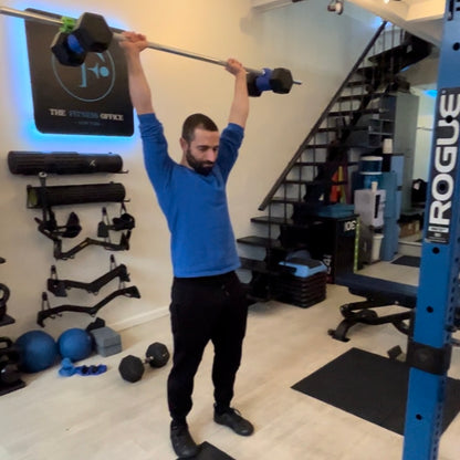 personal trainer performs overhead barbell shoulder press using Dualbell Pair on a standard 1" bar.