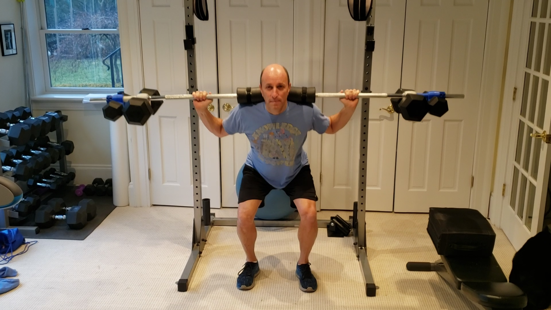 male in home gym doing barbell squats using dumbbells as weight plates connected to bar by Dualbell